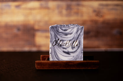 Handcrafted carbon elite men's soap body bar sitting on a wooden stand