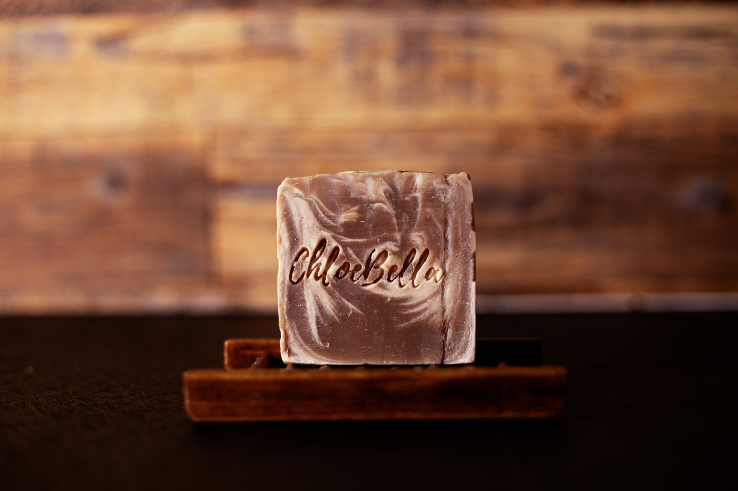 Handcrafted mahogany and teakwood scented men's soap body bar sitting on a wooden stand