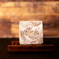 Handcrafted honey and coconut scented soap body bar sitting on a wooden stand