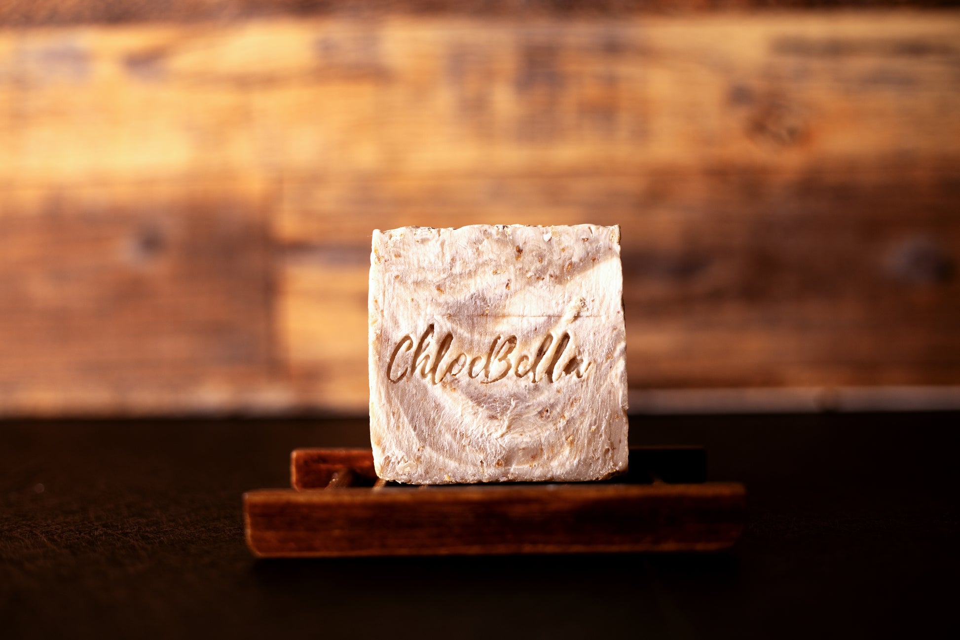 Handcrafted honey and coconut scented soap body bar sitting on a wooden stand