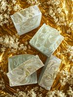 White soap bars on a textured surface with a gold leaf background